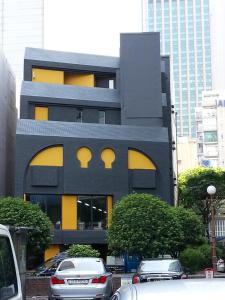 un edificio negro y amarillo con coches estacionados frente a él en Seri Inn Guesthouse en Busan