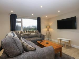 a living room with a couch and a tv at Caledfryn in Benllech