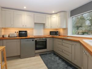 a kitchen with white cabinets and a window at Caledfryn in Benllech