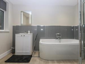 a bathroom with a tub and a sink and a mirror at Caledfryn in Benllech +37 photos