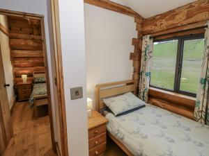a small bedroom with a bed and a window at Douglas Cabin at Salford Court Farm Fishing Cabins in Worcester