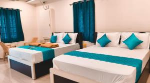 two beds in a room with blue curtains at RCH Home Stay in Rāmeswaram +7 photos