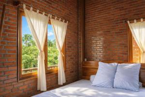 a bed in a brick bedroom with a window at Dream Hill Homestay in Cat Tien