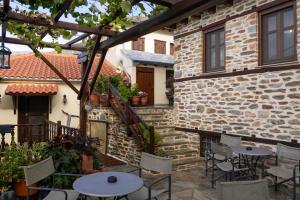 a patio with tables and chairs next to a building at Αρχοντικό Μελλιώ Άγιος Λαυρέντιος in Agios Lavrentios