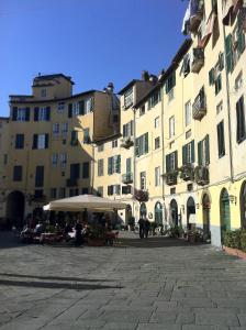 un gruppo di edifici con tavoli e ombrelloni in un cortile di Casa dei Glicini a Lucca