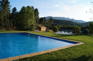 a swimming pool in the middle of a yard with mountains at Camping Maçanet de Cabrenys in Maçanet de Cabrenys