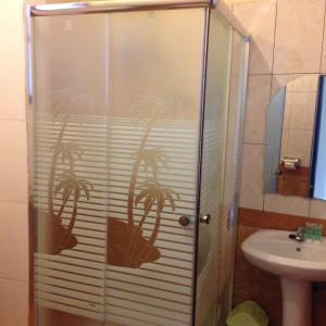 a shower with a glass door with a palm tree on it at J residence Motel in Entebbe