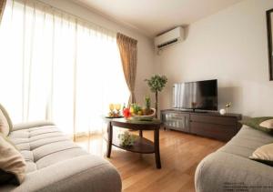 a living room with a couch and a television at Miyakojima Villa Charles in Miyako-jima