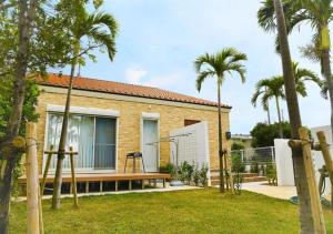 a brick house with palm trees in the yard at Miyakojima Villa Charles in Miyako-jima