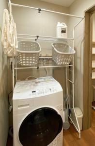 a washing machine in a laundry room with baskets at KYŪKA Chalet in Myoko +12 photos