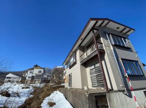 a house sitting on the side of a hill with snow at KYŪKA Chalet in Myoko