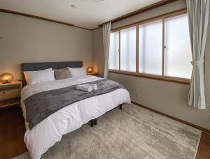 a bedroom with a large bed and a window at KYŪKA Chalet in Myoko