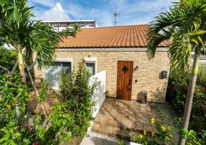 a brick house with a wooden door and palm trees at Miyakojima Villa Charles in Miyako-jima