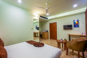 a bedroom with a bed and a desk and a tv at Hotel Maas Residency in Māvelikara