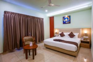 a bedroom with a bed and a chair and a table at Hotel Maas Residency in Māvelikara