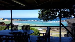 a table and chairs on a porch with a view of the ocean at TussenIn in Eersterivierstrand