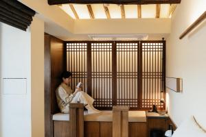 a person sitting in a room with a window at THE CHAE Premium Hanok Stay in Seoul