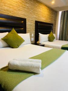 a hotel room with two beds with green pillows at Bayside Hotel 97 Russell Street in Durban