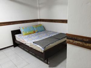 ein kleines Bett mit blauen Kissen in einem Zimmer in der Unterkunft Nur Muslim 2 Homestay At Kota Bharu in Kota Bharu