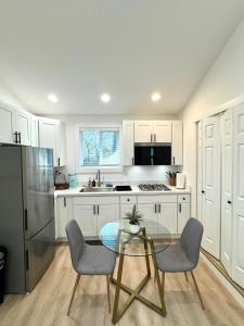 a kitchen with white cabinets and a glass table and chairs at Modern and Cozy Private Studio in Lynnwood