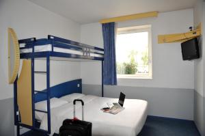 a bedroom with a bunk bed with a laptop and a suitcase at Hotel Ibis Budget Rennes Cesson in Cesson-Sévigné