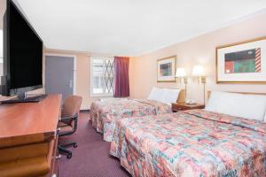 ein Hotelzimmer mit zwei Betten und einem Schreibtisch und einem Fernseher in der Unterkunft Knights Inn - Augusta in Augusta