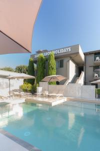 a swimming pool with chairs and umbrellas in front of a building at San Marco Holidays in Lucca