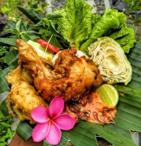 a plate of food with chicken and vegetables and a flower at Sumatra Orangutan Discovery Villa in Bukit Lawang