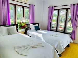 two beds in a room with purple curtains and windows at Baan Golden Resort & Residences in Sam Roi Yot +290 photos