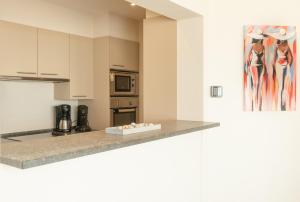 a kitchen with white cabinets and a counter top at Appartement de Panne zeedijk in De Panne