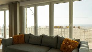 a couch in a living room with a view of the beach at Appartement de Panne zeedijk in De Panne