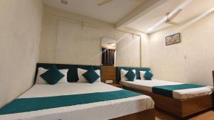 a bedroom with two beds with green and white pillows at Hotel shree Tapovan in Ahmedabad