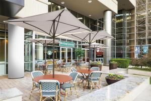 an outdoor patio with tables and chairs with umbrellas at Hyatt Regency - Greenville in Greenville
