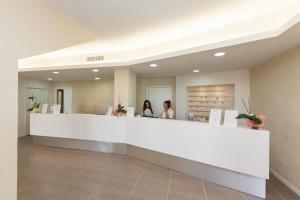 two women standing at a reception counter in a hospital lobby at Porto Ottiolu Resort in Porto Ottiolu