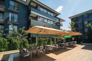 an outdoor patio with tables and chairs and umbrellas at Wyndham Garden Samui Wing in Chaweng