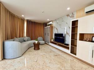a living room with a white couch and a tv at Cannes Ben Tre Hotel in Ben Tre