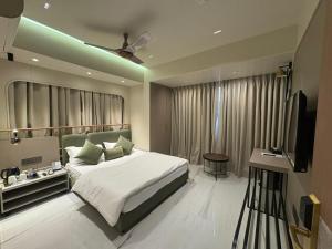 a bedroom with a bed and a flat screen tv at Dormstel - Unit of AHM Hotels & Resorts Pvt Ltd in Vadodara +22 photos