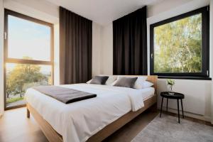 a bedroom with a large bed and large windows at Javorná - Aura a Nord in Čachrov