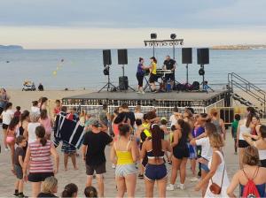 a crowd of people standing on a beach with a stage at Frente Mar in L'Escala