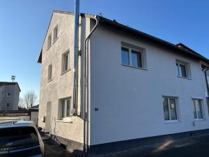 a white house with a car parked next to it at XL Apartment Rödermark 4SZ in Rödermark