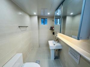 a white bathroom with a sink and a toilet at 하우스 The 쉼 in Suwon
