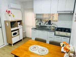 a kitchen with a wooden table and a kitchen with white cabinets at 하우스 The 쉼 in Suwon