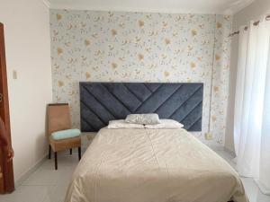 a bedroom with a bed with a blue headboard and a chair at Williston Bly of Gly in Williston