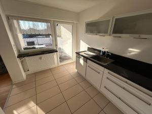 a kitchen with white cabinets and a sink and a window at XL Apartment Rödermark 4SZ in Rödermark +14 photos
