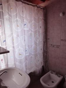 a bathroom with a sink and a toilet and a shower curtain at Complejo Paimun in San Martín de los Andes
