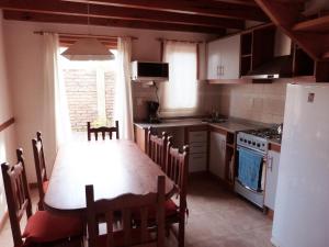 a kitchen with a table and chairs and a kitchen with a refrigerator at Complejo Paimun in San Martín de los Andes