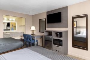 a hotel room with a bed and a desk with a television at Travelodge by Wyndham Banning Casino and Outlet Mall in Banning