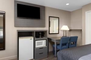 a hotel room with a bed and a desk and a tv at Travelodge by Wyndham Banning Casino and Outlet Mall in Banning