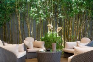 une terrasse avec des chaises, une table et des bambous. dans l'établissement Jade Manotel, à Genève