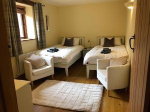 two beds in a room with two chairs and a couch at Old Well Cottage Barn Conversion in Penrith